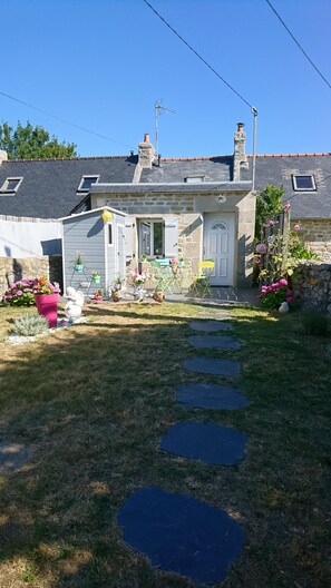 Une maison en pierre avec un jardin, un chemin pavé et un petit étang.