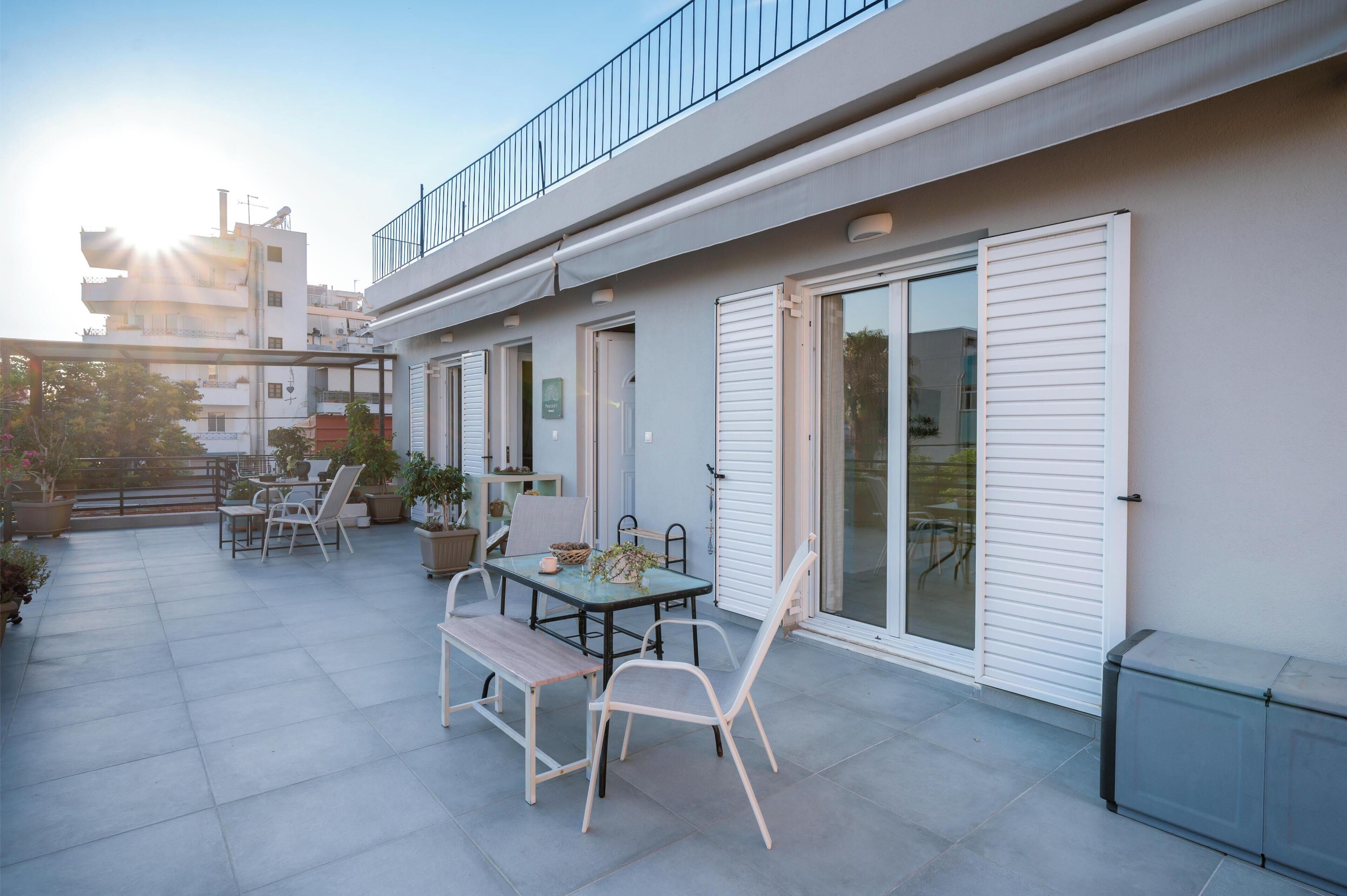 Eine moderne Außenpatio mit Tisch, Stühlen, einer Bank und Blumentöpfen.