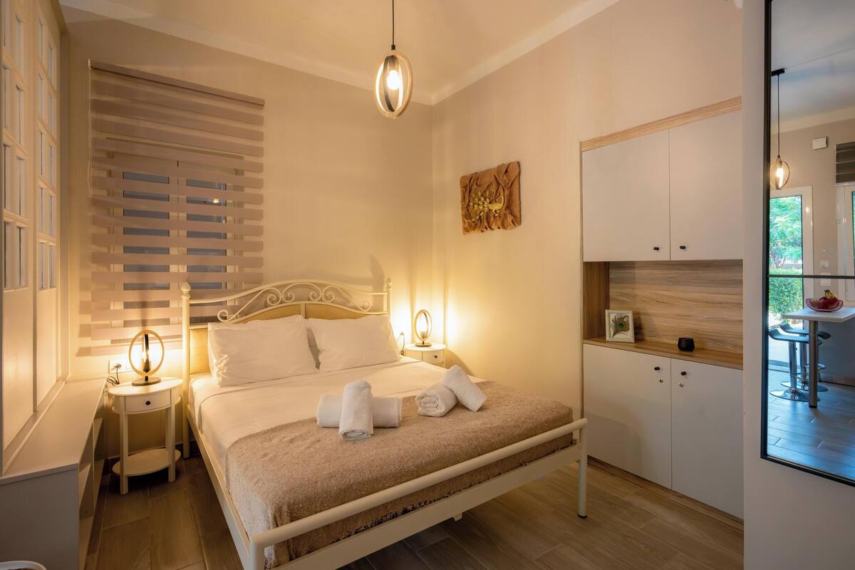 Un dormitorio con cama, mesitas de noche, un espejo y una ventana con persianas.