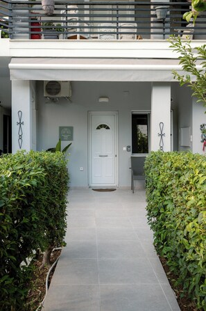 Un ingresso pulito con una porta bianca, una piccola area salotto esterna e un cartello che indica un ambiente adatto agli animali.