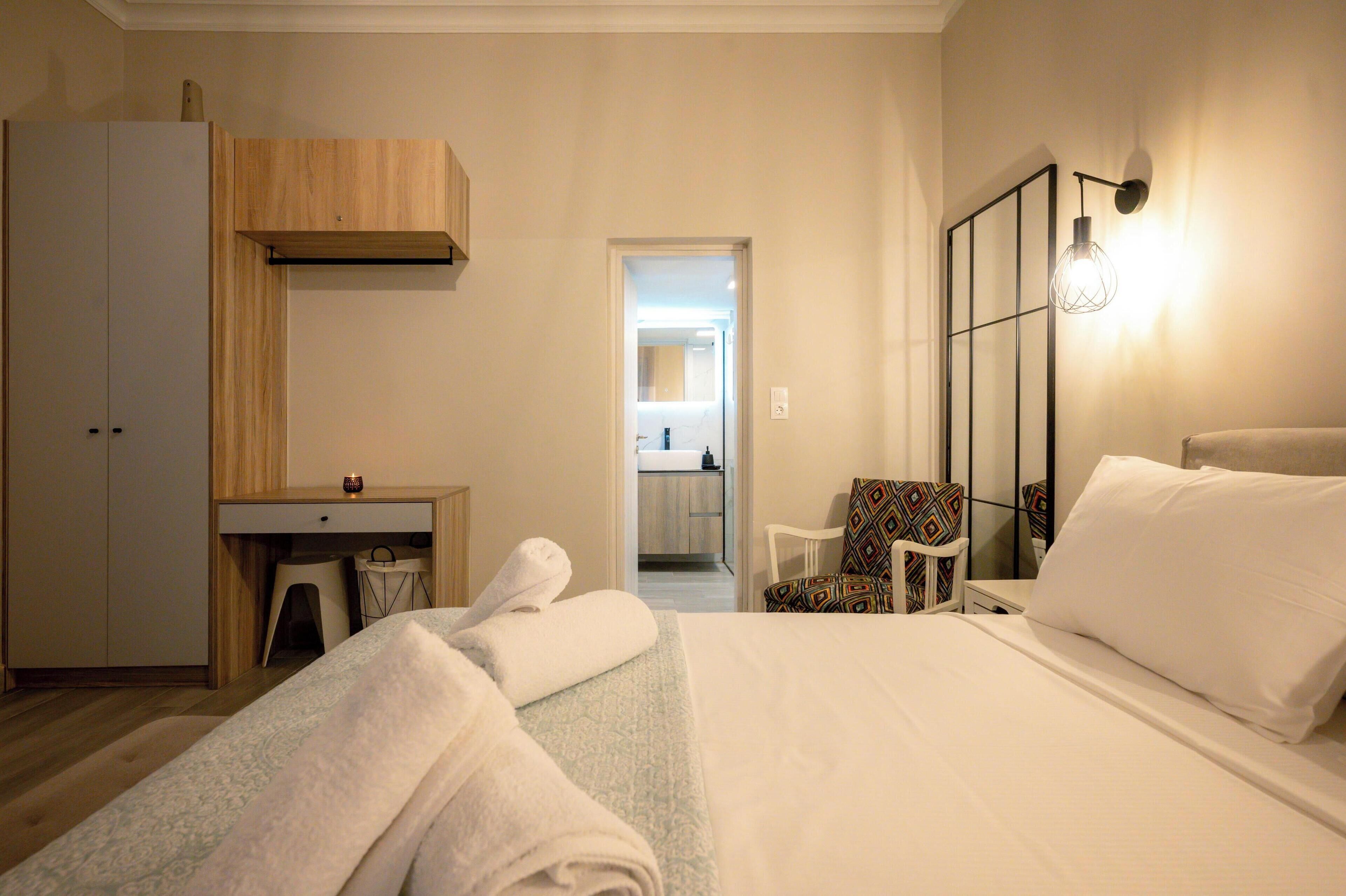 A hotel room with a bed, a desk, a chair, and a mirror.