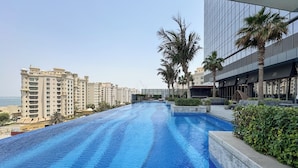 A swimming pool with a view of high-rise buildings and palm trees. - PVH - Modern Studio - Palm Tower (Dubai)