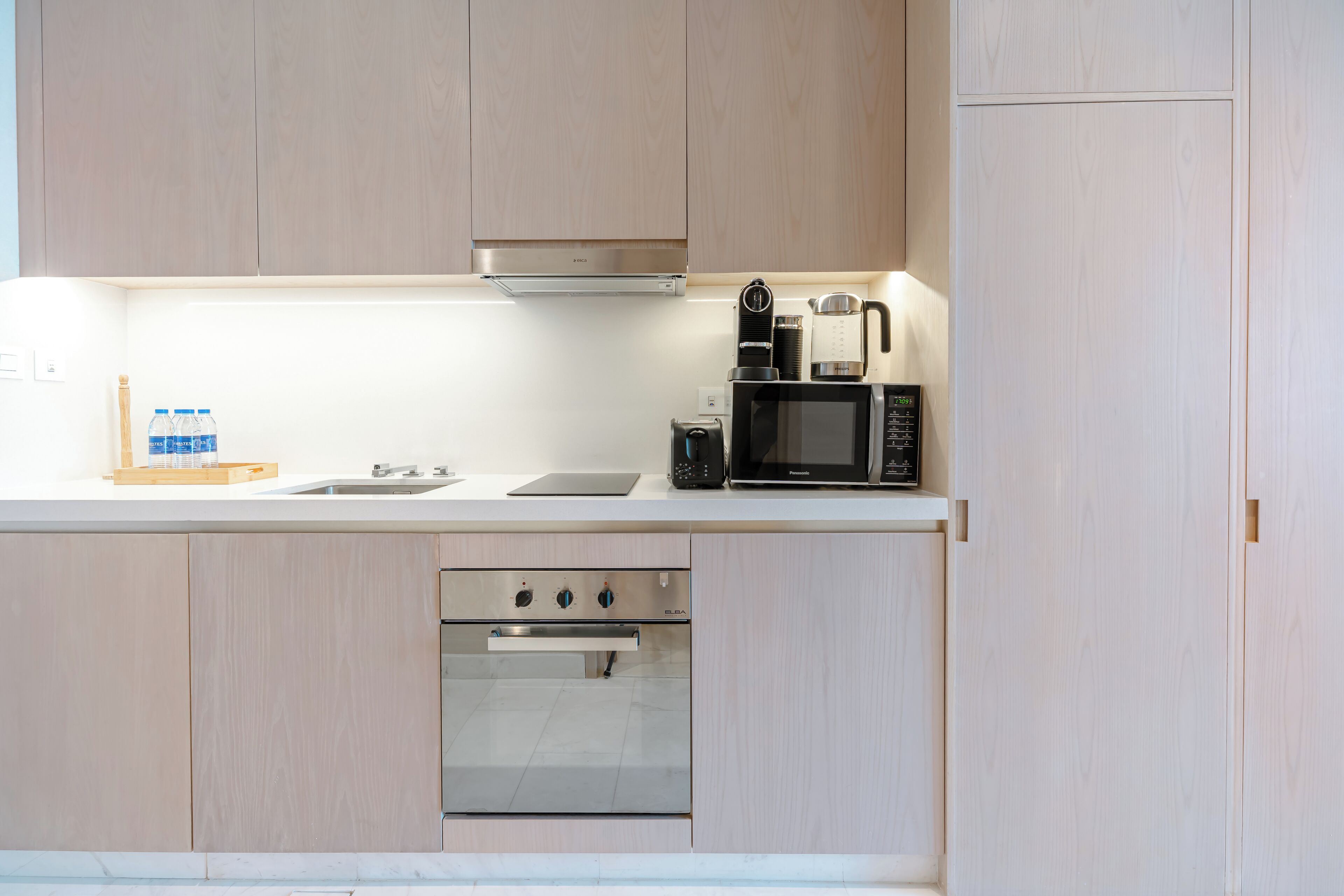 A modern kitchen with a built-in oven, microwave, and coffee maker.