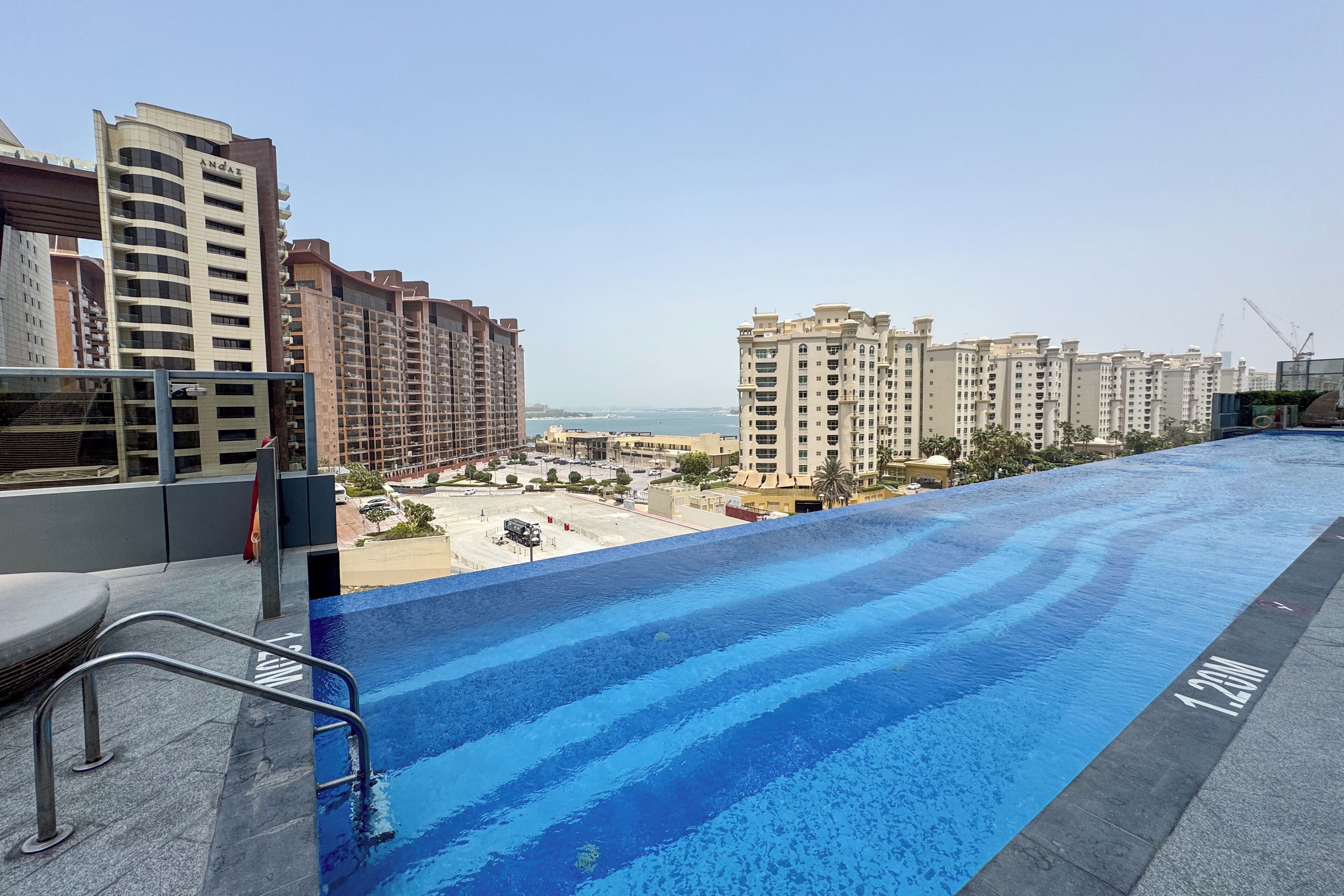 Ein Dachpool mit Blick auf hohe Gebäude und eine entfernte Küstenlinie.