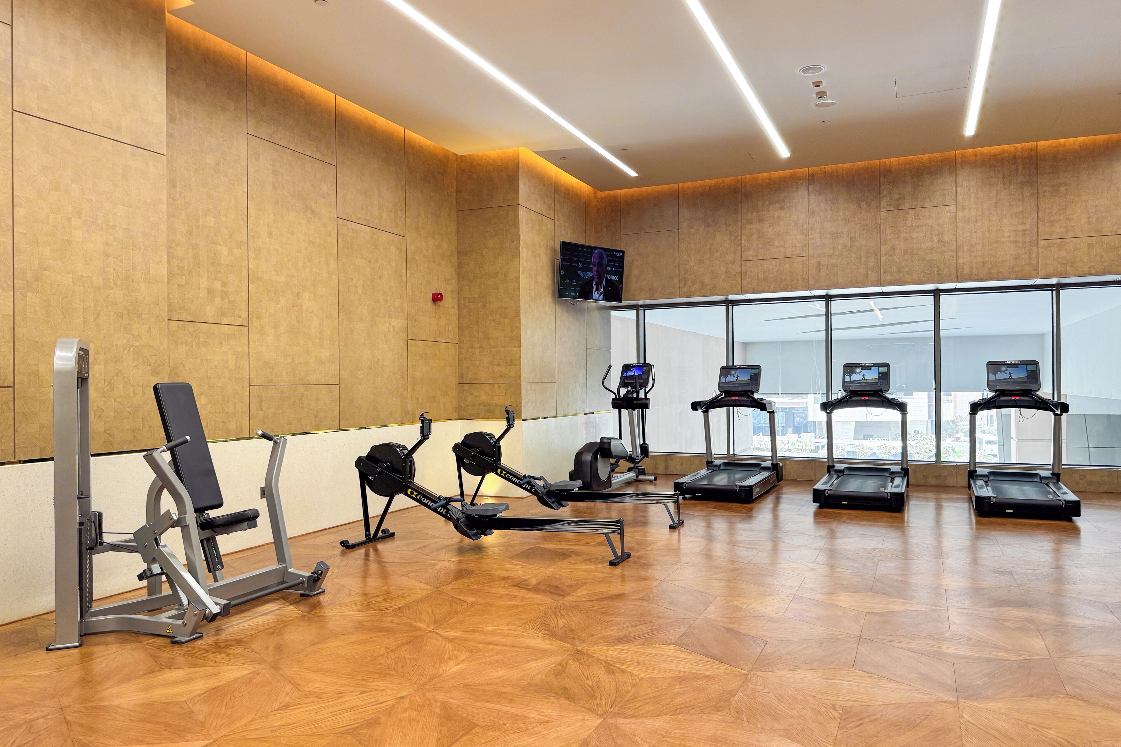 Et fitnesscenter med træningsudstyr, store vinduer og et moderne design.