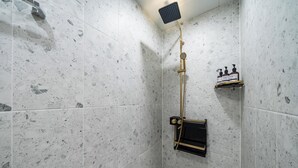 A shower with a handheld showerhead, a wall-mounted control panel, and a soap dispenser shelf. - JIncheon hotel hue (Jincheon)