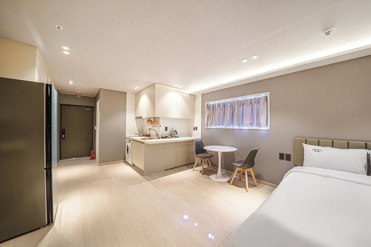 Una habitación de hotel moderna con cama, una pequeña zona de comedor y una kitchenette.