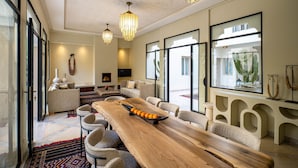 Un salón amplio con una larga mesa de madera, asientos cómodos y ventanas grandes que ofrecen vistas al exterior.
