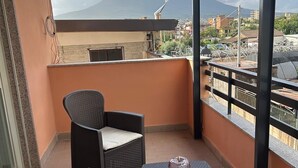 A balcony with wicker furniture and a view of a mountain.