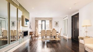 A spacious living room with a dark wooden floor, a dining area with a table and chairs, a large mirror, and a sofa. - The Primrose Hill Elegant House (Greater London)