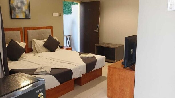 A hotel room with two beds, a TV, a minibar, and a ceiling fan. - REEMZ BEACH HEAVEN HOTEL (Anjuna)