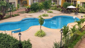 A swimming pool surrounded by greenery, with a building in the background. - REEMZ BEACH HEAVEN HOTEL (Anjuna)