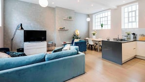 Ein modernes Wohnzimmer mit einer Couch, Fernseher und Essbereich.