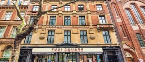 A building with a Thai Square sign, featuring a traditional facade with multiple windows and a prominent entrance.