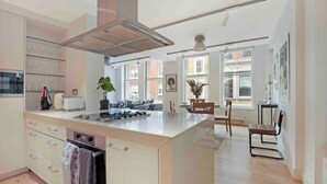A modern kitchen with an island, built-in appliances, and large windows offering views of the city.