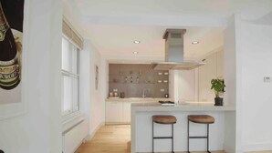 A modern kitchen with a central island, bar stools, and a large window.