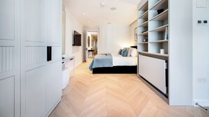 A modern bedroom with a bed, bedside tables, a wardrobe, and built-in shelving. - Soak in the Spalike Marble Bath at Plush Penthouse (Greater London)