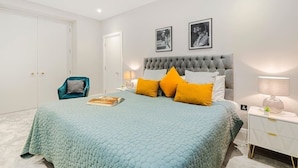 Une chambre à coucher avec un lit, une table de chevet, une chaise et deux tableaux encadrés accrochés au mur.
