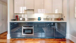 A modern kitchen with a built-in oven, a coffee maker, and a toaster on the countertop. - The Cosy Compact flat in Mayfair (Greater London)