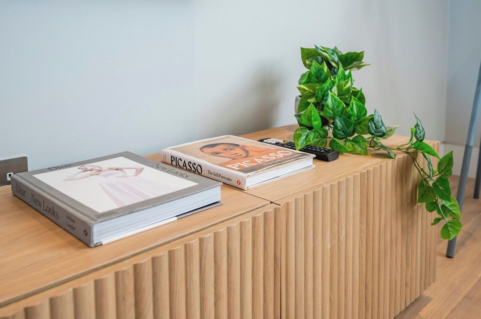 A wooden reception desk with two books, a remote control, and a potted plant.
