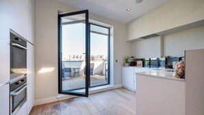 A modern kitchen with a sliding glass door leading to a balcony, built-in appliances, and a view of the cityscape. - Best Penthouse in Bloomsbury (Greater London)
