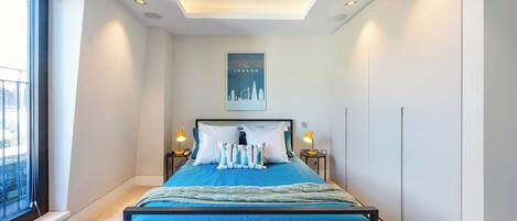 A modern bedroom with a large bed, two bedside tables, a skylight, and a cityscape poster on the wall.