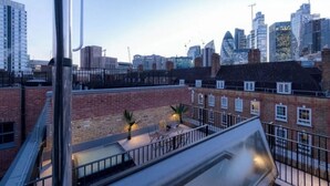 A rooftop terrace with a view of the city skyline, including modern buildings and construction cranes. - A Slick House Trendy Spitafields (Greater London)