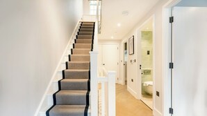 A staircase with carpeted steps and white railings leading to a room with a toilet and a shower. - A Slick House Trendy Spitafields (Greater London)