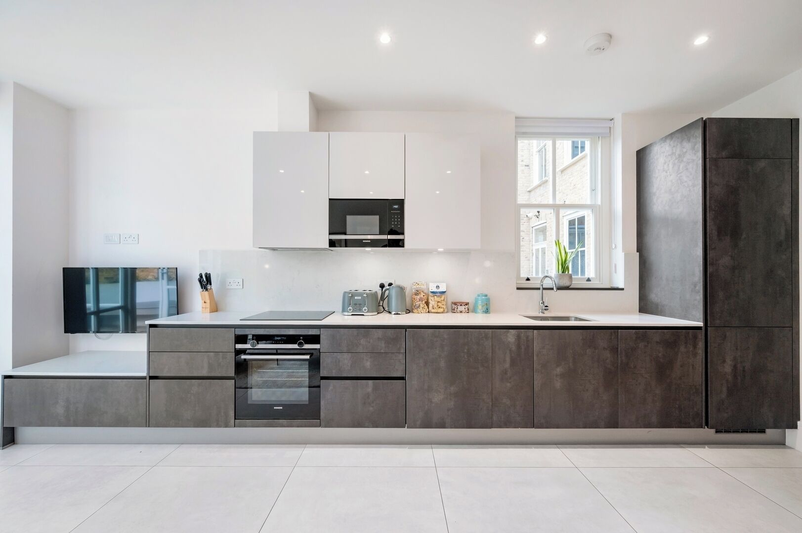 A modern kitchen with a built-in oven, microwave, and a large window.
