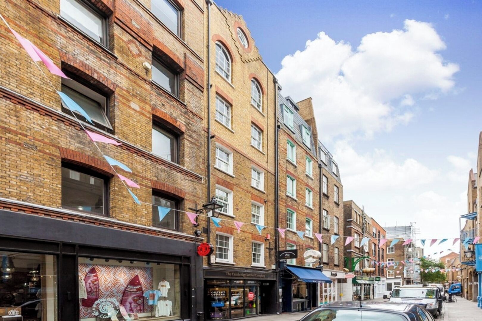 A street view with brick buildings, shops, and a clear sky.