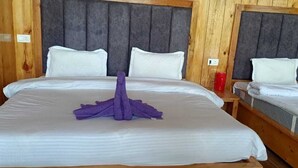 Ein Hotelzimmer mit einem großen Bett, zwei Einzelbetten, Holzwänden und einem grauen Kopfteil.