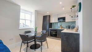Une cuisine moderne dotée d’un îlot central, d’un four encastré et d’un four à micro-ondes. On y trouve également un coin repas avec une table ronde et des chaises.
