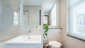 Ein modernes Badezimmer mit Waschbecken, Toilette und Spiegel in Weiß.