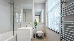 Ein modernes Badezimmer mit Duschkabine aus Glas, einem weißen Waschbecken und einer Toilette.