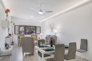 Una sala de estar moderna con comedor, ventilador de techo y vistas al exterior.