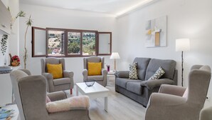 A modern living room with a sofa, armchairs, a coffee table, and a view of a landscaped area through a window. - Holiday Home 'Buena Vista House' with Mountain View, Private Terrace and Wi-Fi (Santa Brígida)