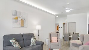 A modern living room with a grey sofa, armchairs, a dining table, and a ceiling fan. - Holiday Home 'Buena Vista House' with Mountain View, Private Terrace and Wi-Fi (Santa Brígida)
