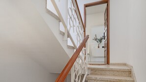 A staircase with a wooden handrail and a decorative white railing, leading to a room with a white wall and a potted plant. - Holiday Home 'Buena Vista House' with Mountain View, Private Terrace and Wi-Fi (Santa Brígida)