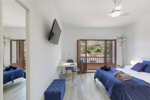 Une chambre avec deux lits, un bureau, une chaise, une télévision et un balcon avec vue.
