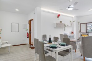 Un espace repas moderne avec une table blanche, des chaises grises et un ventilateur de plafond.