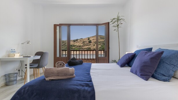 A bedroom with a bed, a desk, a chair, a plant, and a view of a landscape through a door. - Holiday Home 'Buena Vista House' with Mountain View, Private Terrace and Wi-Fi (Santa Brígida)
