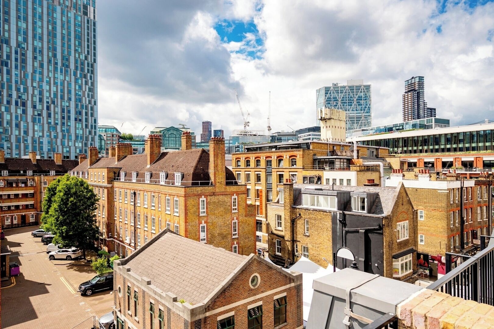 Un paysage urbain où se côtoient des bâtiments modernes et traditionnels, notamment un imposant gratte-ciel en verre et des constructions plus anciennes en brique.