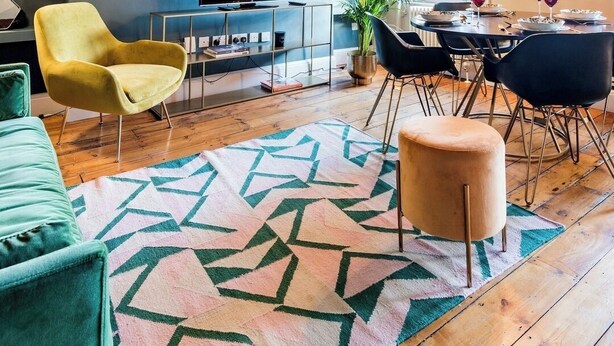 A modern living room with exposed wooden beams, a large TV, and a dining area with a table set for two. - Embrace authenticity and quirky charm (Greater London)