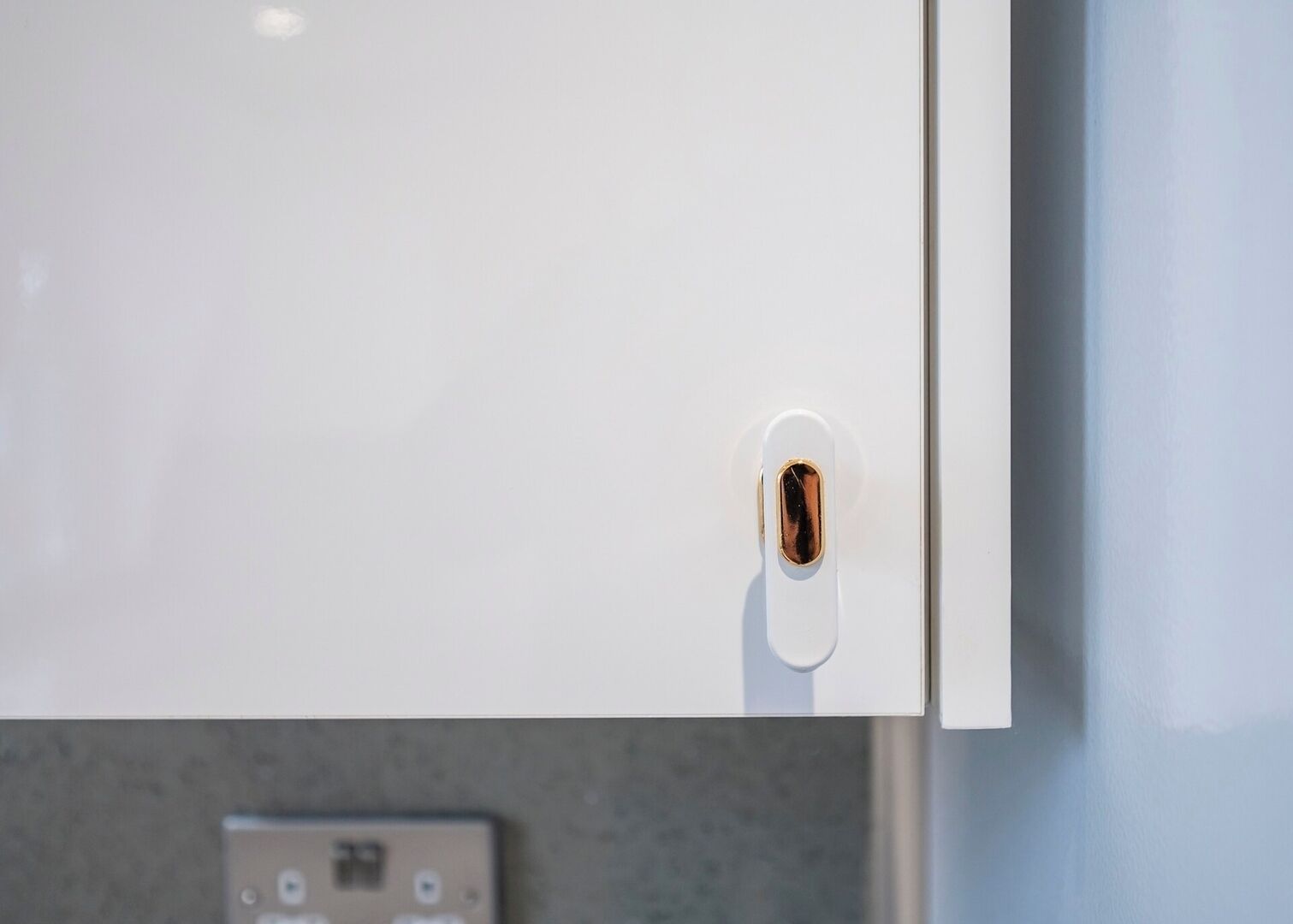 A white door with a keyhole and a small electronic device below it.