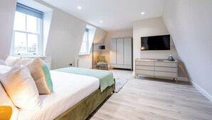 A modern bedroom with a large bed, a wardrobe, a desk, and a TV. - Angel Brand New Penthouse (Greater London)