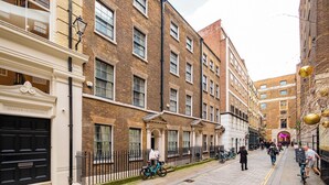 A narrow street lined with brick buildings, some with balconies and others with ground-level entrances. - The Liverpool Trendy House (Greater London)