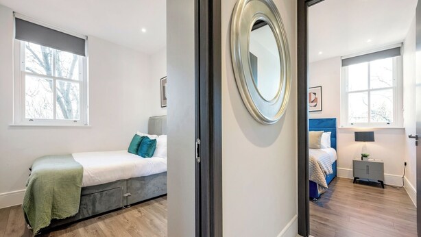 A modern bedroom with a bed, bedside table, and a mirror.