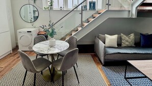 Et moderne køkken med spiseområde, en trappe og en stue med sofa.