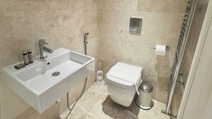 Et badeværelse med en hvid vask, toilet og bruseområde.