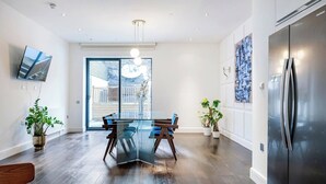 A modern kitchen with a glass dining table, stainless steel refrigerator, and potted plants. - Deluxe and Peace in Primrose Hill (Greater London)